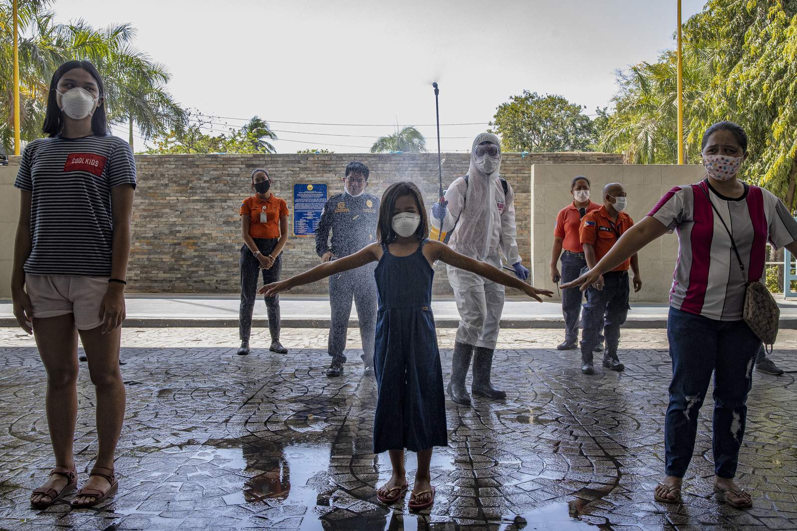 Masked children in a fountain surround a person wearing PPE